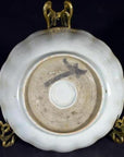 Close-up of the underside of an antique hand painted Chinese porcelain plate on a brass stand against a dark background.