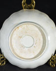 Close-up of the underside of an antique hand-painted Chinese porcelain plate on an ornate brass stand.