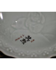 Close-up of antique hand painted embossed Japanese porcelain plate with red characters and unique art in the center.