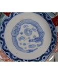 Close-up of antique Japanese Imari porcelain bowl, hand painted with blue dragon motif and red, blue rim accents.