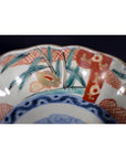 Close-up of a multicolored porcelain Japanese Imari bowl with hand painted vibrant floral designs on the scalloped rim.