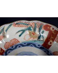 Close-up of red, blue, and green hand painted porcelain Japanese Imari bowl with intricate decorative motifs.
