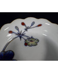 Close-up of four multicolored porcelain Japanese Imari bowls with scalloped edges and floral rim designs.
