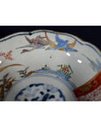 Close-up of antique Japanese Imari porcelain bowl, hand painted with blue, red, green and gold birds and landscapes.