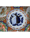 Close-up of blue, red, and green hand painted floral patterns on antique Japanese Imari porcelain bowl.