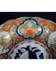Close-up of red, blue, green, and gold floral Japanese Imari porcelain bowl, hand painted antique.