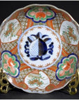 Close-up of antique Japanese Imari porcelain bowl with red, green, and blue floral patterns and central blue fish.