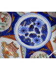 Blue, white, orange, and gold porcelain Imari bowl with ornate hand-painted circular designs, close-up view.