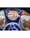 Close-up of a multicolor porcelain Japanese Imari bowl with hand painted intricate patterns and a scenic center design.