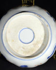 Close-up of the bottom of an antique hand painted Japanese Imari porcelain bowl with blue mark on metal stand.
