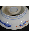 Close-up of the underside of a white and blue porcelain bowl with hand-painted patterns and scalloped edge.
