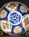 Blue, red, and gold hand painted Japanese Imari porcelain bowl with floral patterns displayed on a stand.