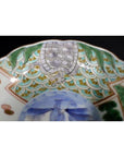 Close-up of a green and gold hand painted Japanese Imari porcelain bowl with turtle motif and ornate rim.