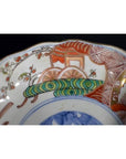 Close-up of a red, green, and blue hand painted porcelain Japanese Imari bowl with antique detailing.