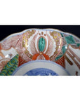 Close-up of a red, green, and gold hand painted porcelain Japanese Imari bowl with antique patterns.
