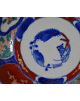 Close-up of four antique Imari porcelain bowls with blue, red, and green hand-painted floral and fish designs.