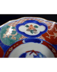Close-up of four antique hand-painted Imari porcelain bowls with vivid floral and geometric patterns.