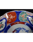 Close-up of four antique porcelain Imari bowls with red, blue, and green hand-painted floral rim patterns.