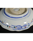 Porcelain bowls underside, set of four, hand-painted blue lines with orange and green accents, close-up.