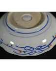 Blue and orange-green porcelain bowls set of four, hand-painted with wavy lines and floral accents near base.