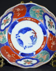 Close-up of four antique Imari porcelain bowls with vivid red, blue, and green floral and bird designs.