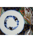 Close-up of blue, red, green, and gold hand painted floral patterns on antique Japanese Imari porcelain bowl.
