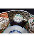 Close-up of colorful hand painted Imari porcelain bowl with floral patterns and black, gold-kintsugi accents.