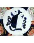Blue and white porcelain Imari bowl with hand painted floral patterns and geometric center, close-up view.