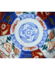Close-up of a blue, red, and gold hand painted porcelain Japanese Imari bowl with floral and geometric patterns.