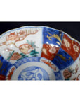 Close-up of antique Japanese Imari porcelain bowl with red, blue, and gold hand-painted floral patterns.
