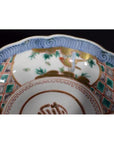 Close-up of colorful hand-painted Japanese Imari porcelain bowl with bird and bamboo patterns.