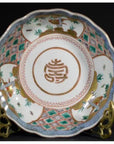 Blue and white porcelain Japanese Imari bowl with gold symbol and intricate patterns on a metal stand, close-up.