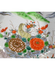 Close-up of a colorful porcelain Imari bowl with hand painted flowers, green leaves, and a yellow bird design.