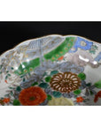 Close-up of a black porcelain Japanese Imari bowl with hand painted vibrant floral and bird patterns.
