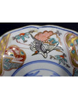 Close-up of a multicolored porcelain Japanese Imari bowl with hand painted bird and floral designs and a vibrant rim.