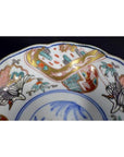 Close-up of a multicolor porcelain Imari bowl with hand painted cranes, floral patterns, and detailed edge designs.