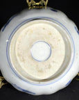 White and blue porcelain bowl underside on brass stand, hand painted Japanese Imari style, indoor setting.