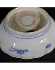 Blue and white porcelain bowl with hand-painted floral design, upside down on a dark surface.