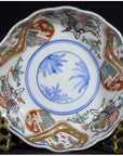 Red, blue, gold, and green hand painted Japanese Imari porcelain bowl with crane and floral designs, close-up view.