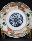 Close-up of blue, green, and orange hand painted Japanese Imari porcelain bowl on brass stand.