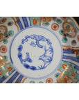 Blue, red, and gold hand painted Imari porcelain bowl with central floral design, close-up view.