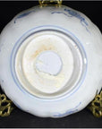 Close-up of blue and white porcelain Imari bowl bottom, hand painted, displayed on a brass stand.