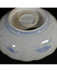 Blue and white porcelain bowl with hand-painted motifs, upside down on black surface.