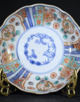 Blue and red hand painted Japanese Imari porcelain bowl on ornate metal stand, close-up.