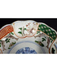 Close-up of colorful hand painted Japanese Imari porcelain bowl with scalloped rim and intricate patterns.