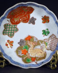 Blue and white hand painted Japanese Imari porcelain bowl on ornate brass stand, close-up.