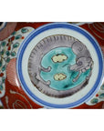 Close-up of red, blue, and white Imari porcelain bowl with hand-painted rat or mouse among clouds design.