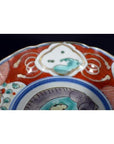 Close-up of a colorful hand painted Japanese Imari porcelain bowl with floral and geometric patterns.