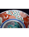 Close-up of a multicolored porcelain Japanese Imari bowl with red, white, green, and blue hand-painted floral designs.