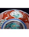 Close-up of a red, blue, and green floral Japanese Imari porcelain bowl with hand-painted designs.